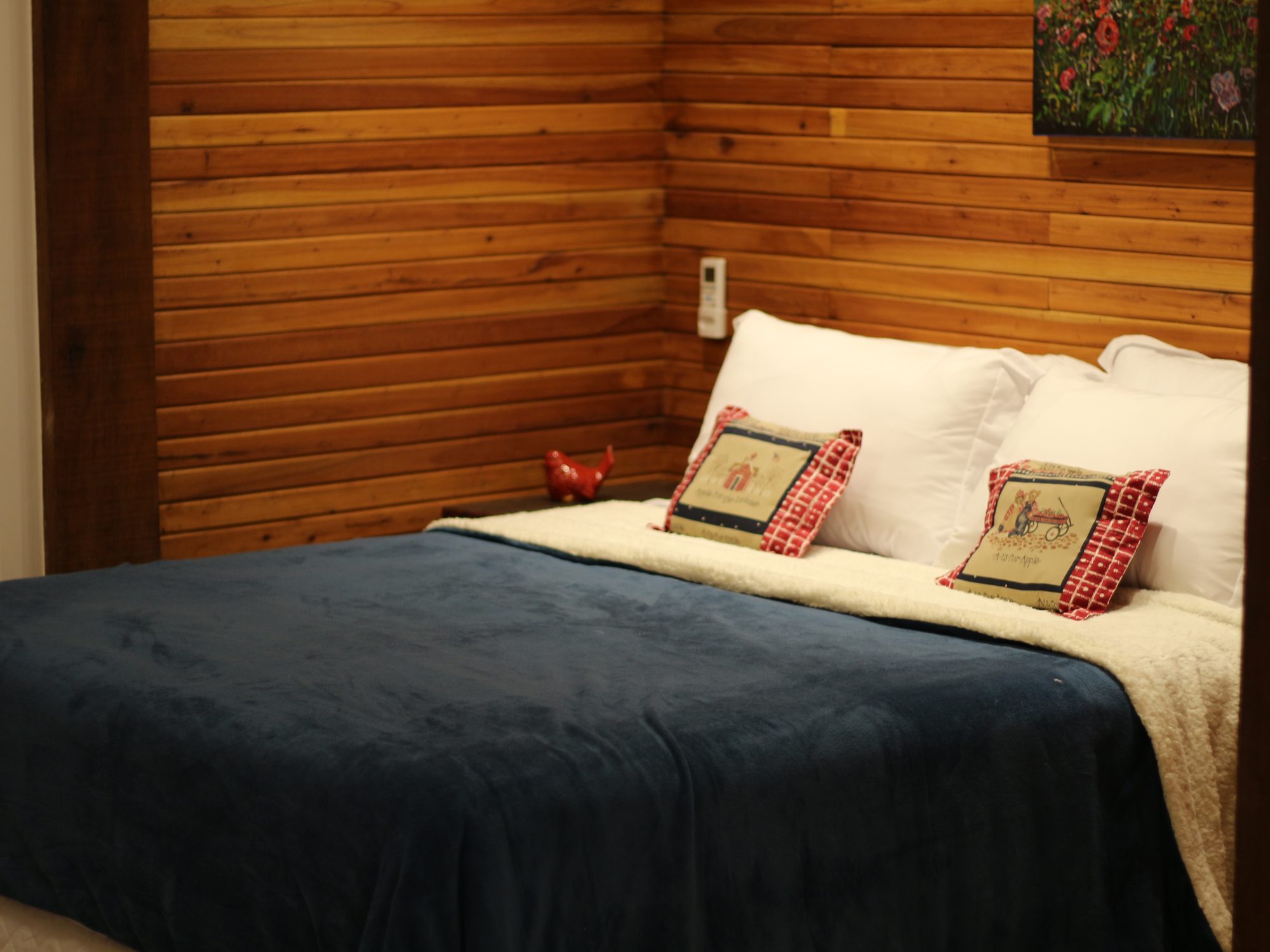 Suíte Embaúba — cama Queen Size com parede de madeira